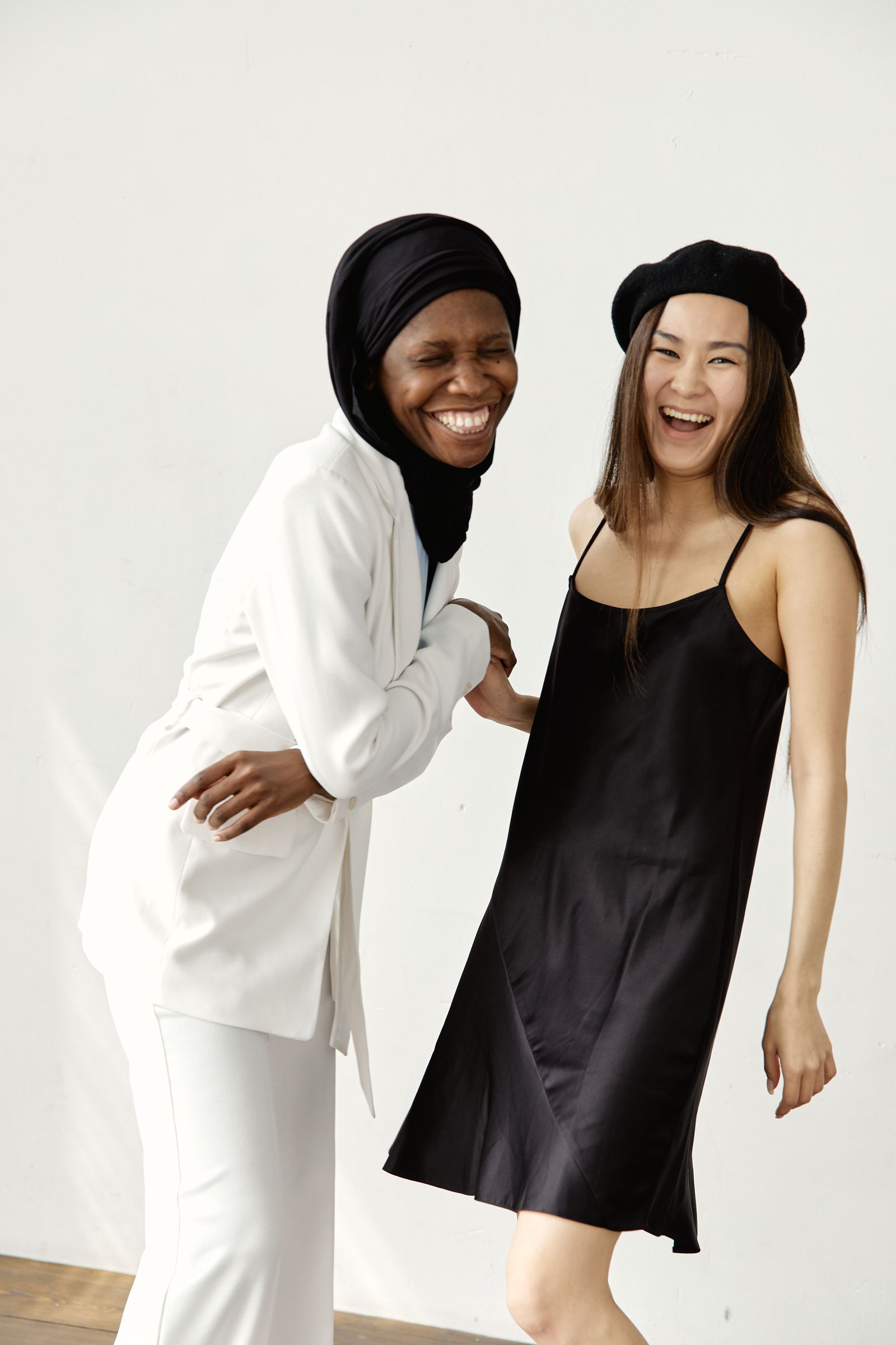 Two friends in their early forties laughing together in bright studio light